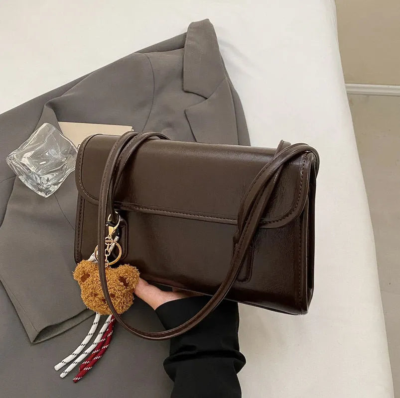 Brown women's PU leather shoulder bag with square shape, pendant detail, and double shoulder straps