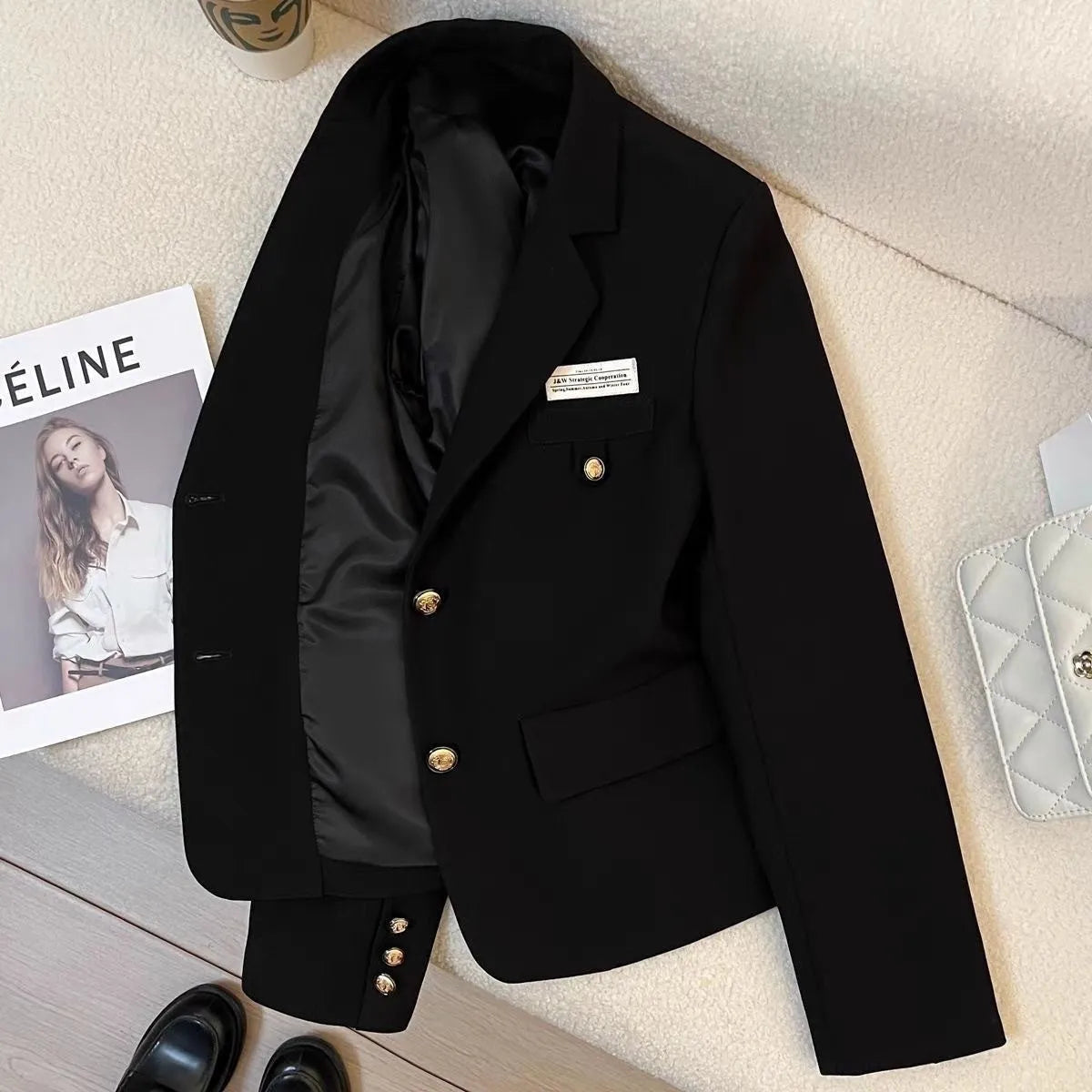 Black loose-fit women's short suit coat with front pockets on a hanger.