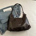 Women's textured PU leather shoulder bag with single strap and mobile phone compartment in black colour