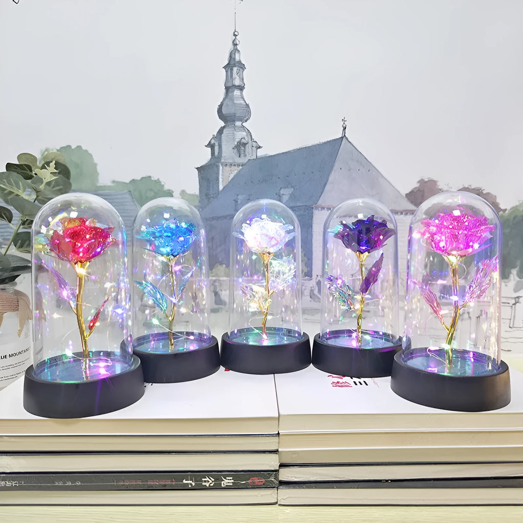 Small glass cover night lamp with plastic flowers on a black base, showing coloured light illumination.