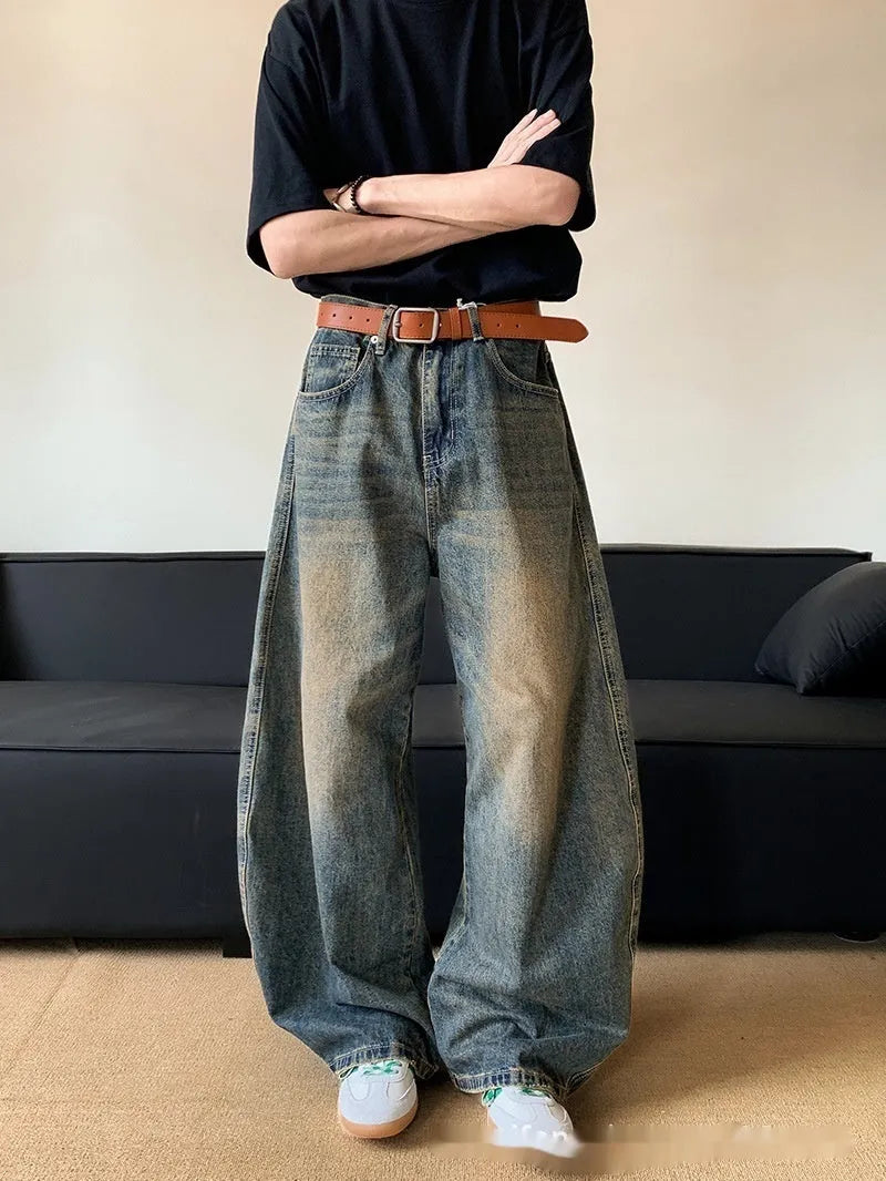 Man wearing retro blue distressed denim jeans with a slim-fit wide-leg cut.