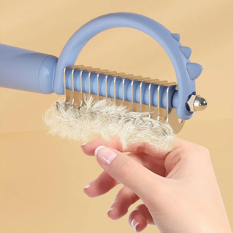 Blue dinosaur-shaped cat brush with stainless steel bristles and self-cleaning button