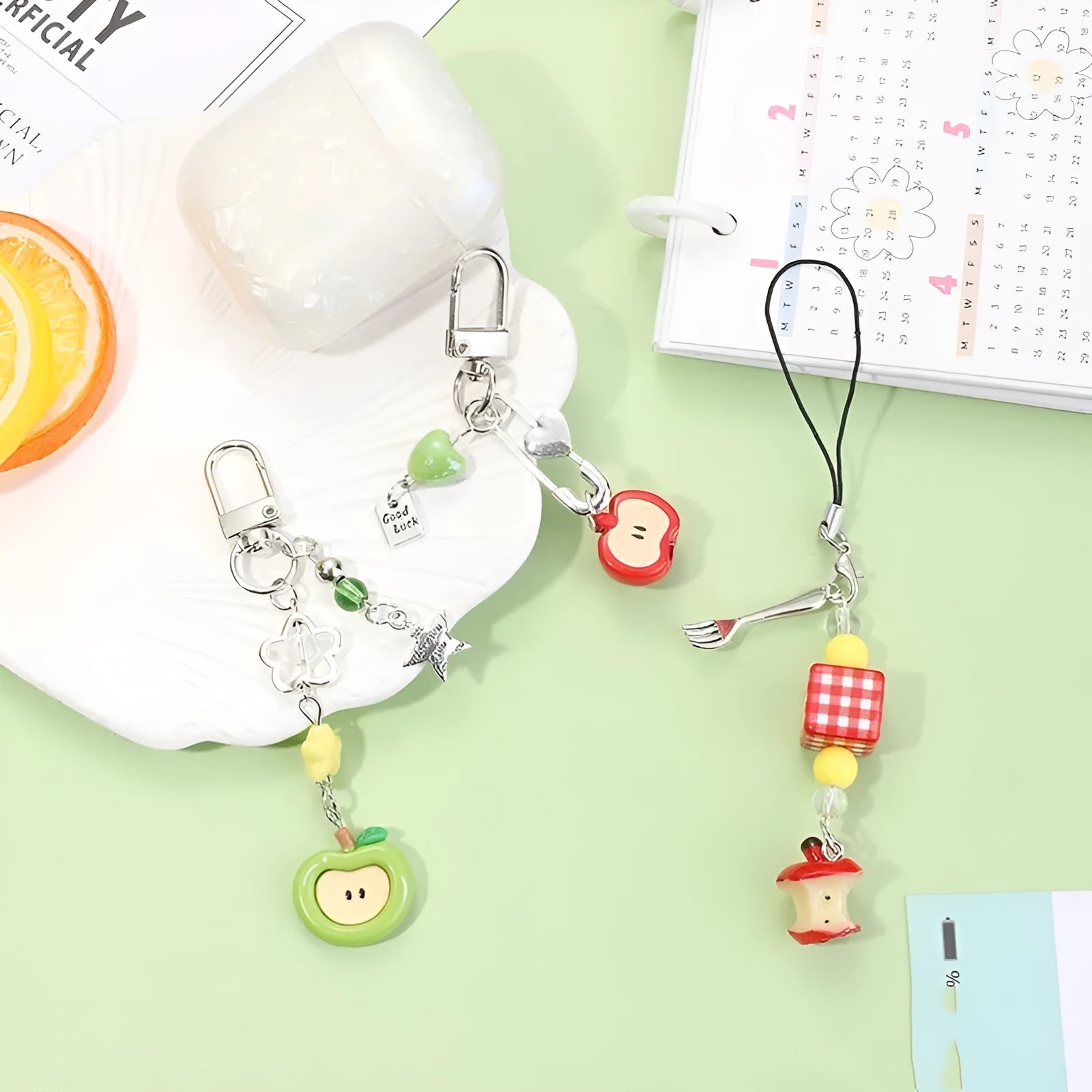 Plastic resin fruit pattern phone charm keychain pendant with apple and strawberry designs on a white rope.