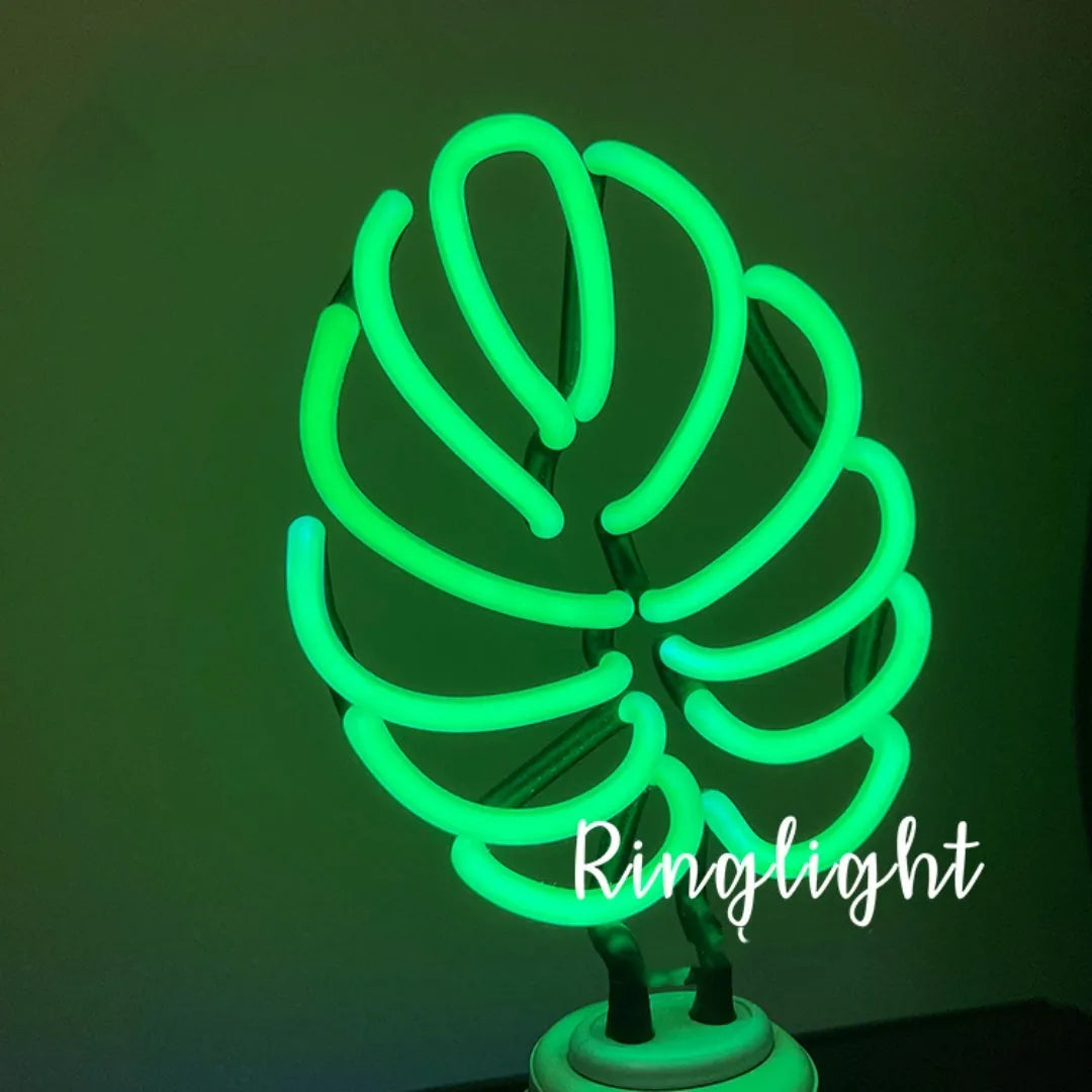 White bamboo-shaped desktop lamp with green light tube on a wooden desk.