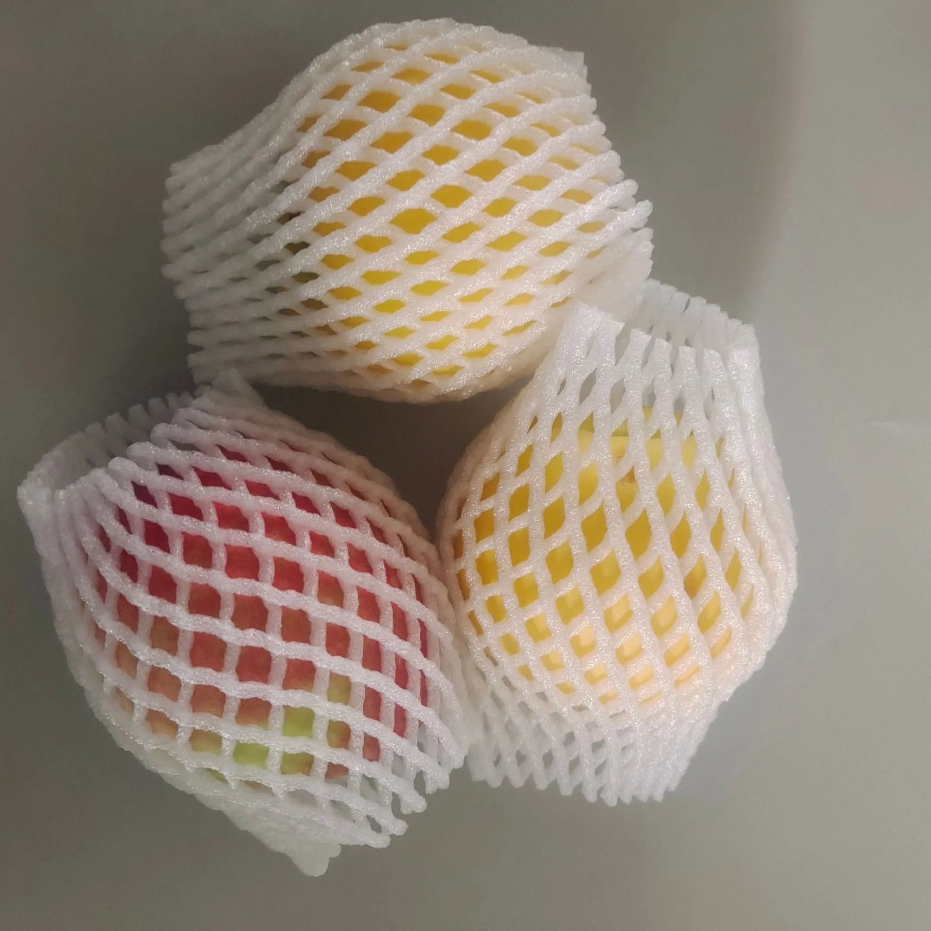 White foam and elastic net protective case for fruits, shown with size options for apples and pears.