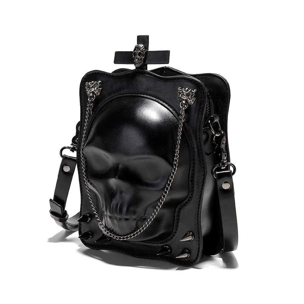 Black mini square crossbody bag with embossed skull design, decorative stitching, rivets, and chain details.