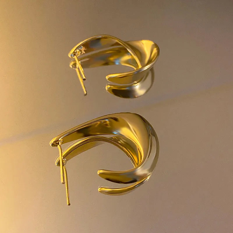 A pair of round, twisted geometric metal earrings with a gold electroplated finish.