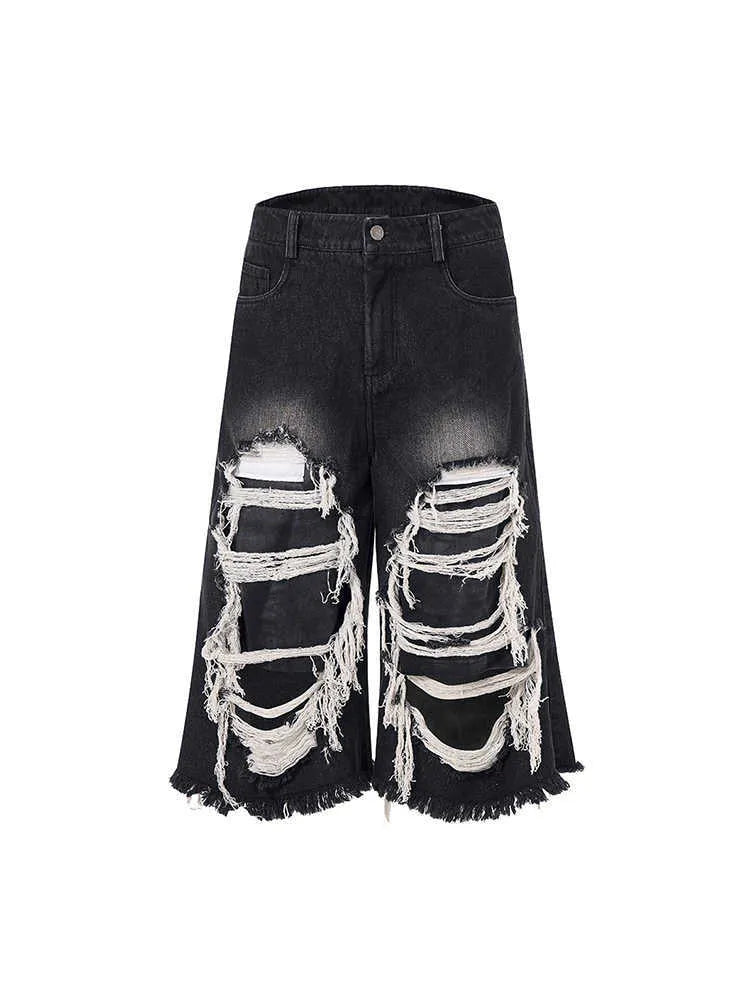 Black cropped wide-leg jeans with ripped patch detail on the leg, showing a mid-high waist and loose fit.