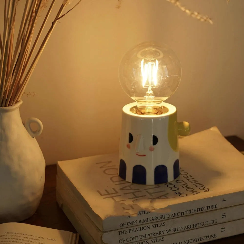 Handmade ceramic table lamp with a ball-shaped headlight on a neutral background.