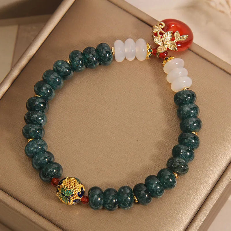 Blue water jade bead bracelet with red agate peace buckle closure and rhinestone details