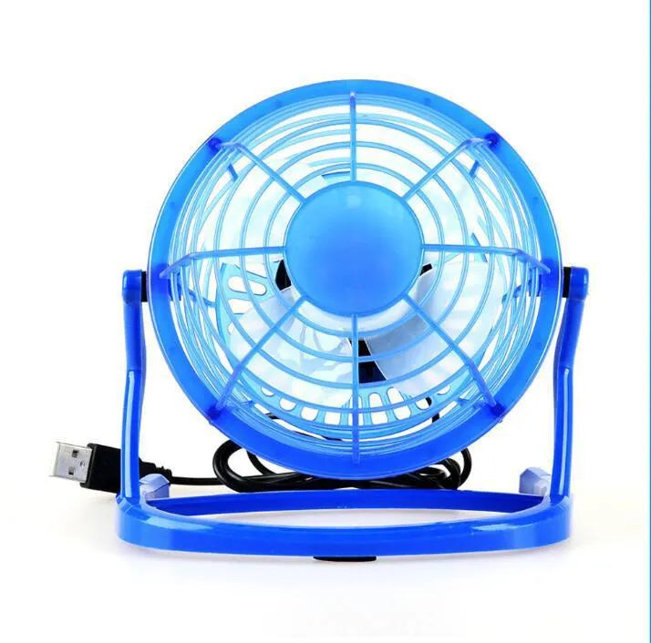 Mini black USB desk fan with adjustable angle on wooden desk next to laptop