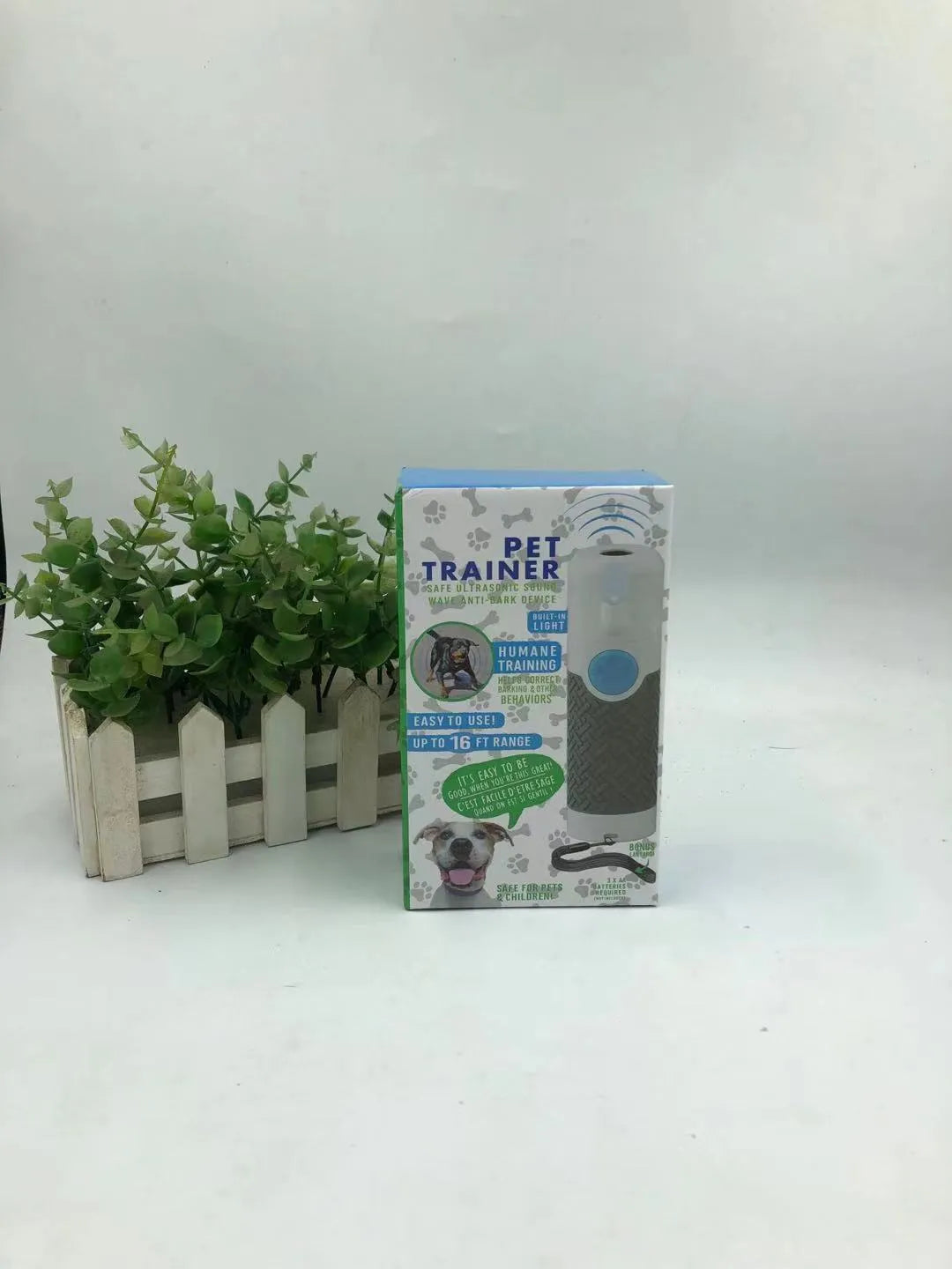 White handheld ultrasonic dog bark stop trainer on a plain background.