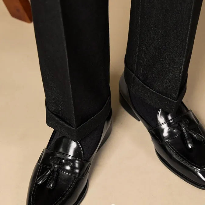 Men's black and brown tassel loafers with polished leather uppers and rubber soles
