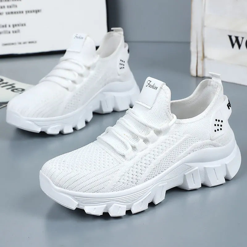 Women's white Flyknit sneaker with thick sole and lace-up front, shown on a neutral background