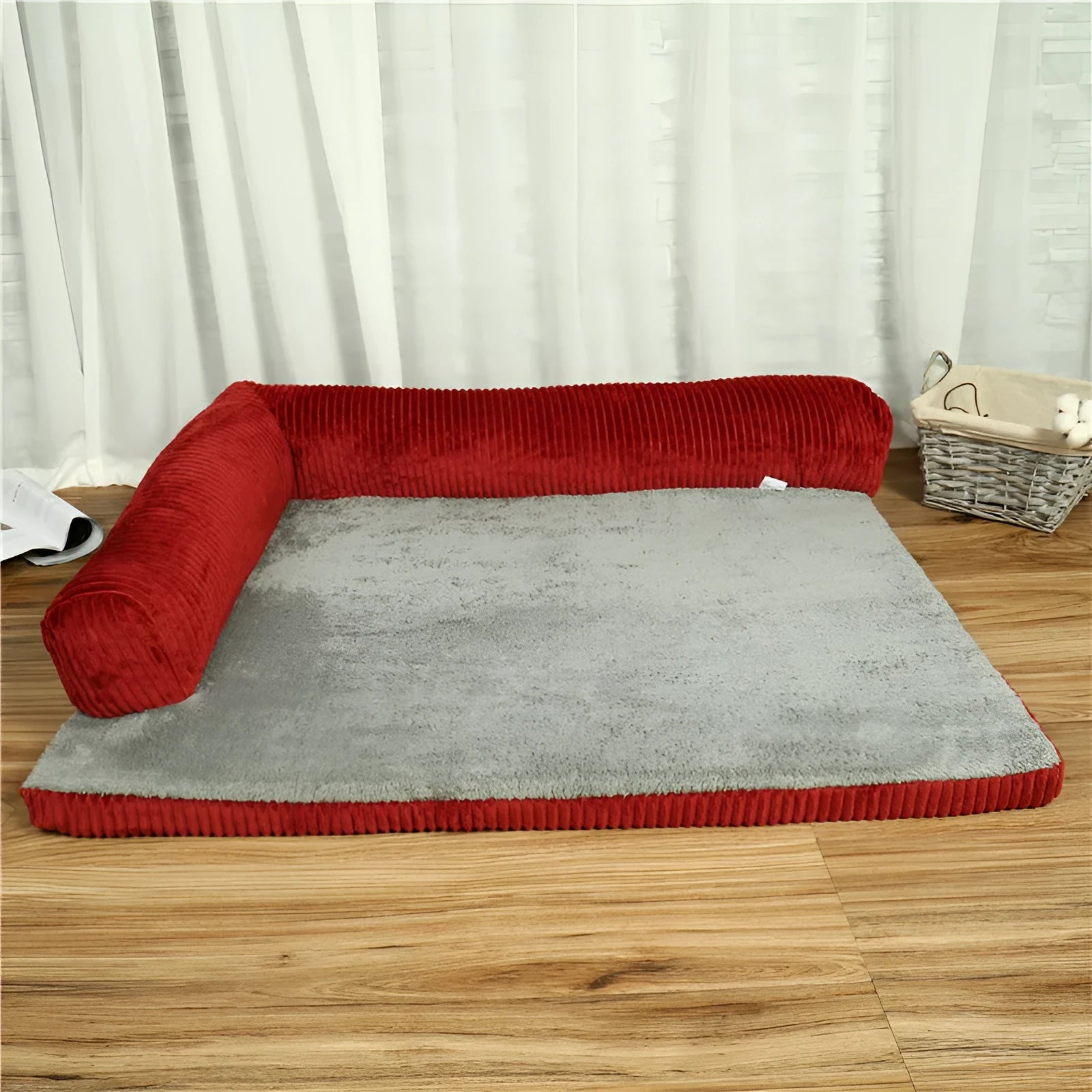 A corduroy pet sofa dog bed with a raised bolster, shown in a grey colour on a wooden floor.