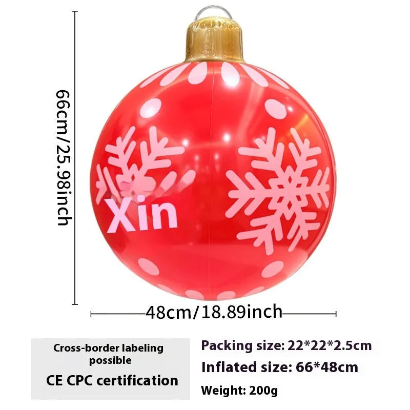 Large red inflatable Christmas ball with snowflake pattern and flash light, shown with a hand pump in a garden setting.