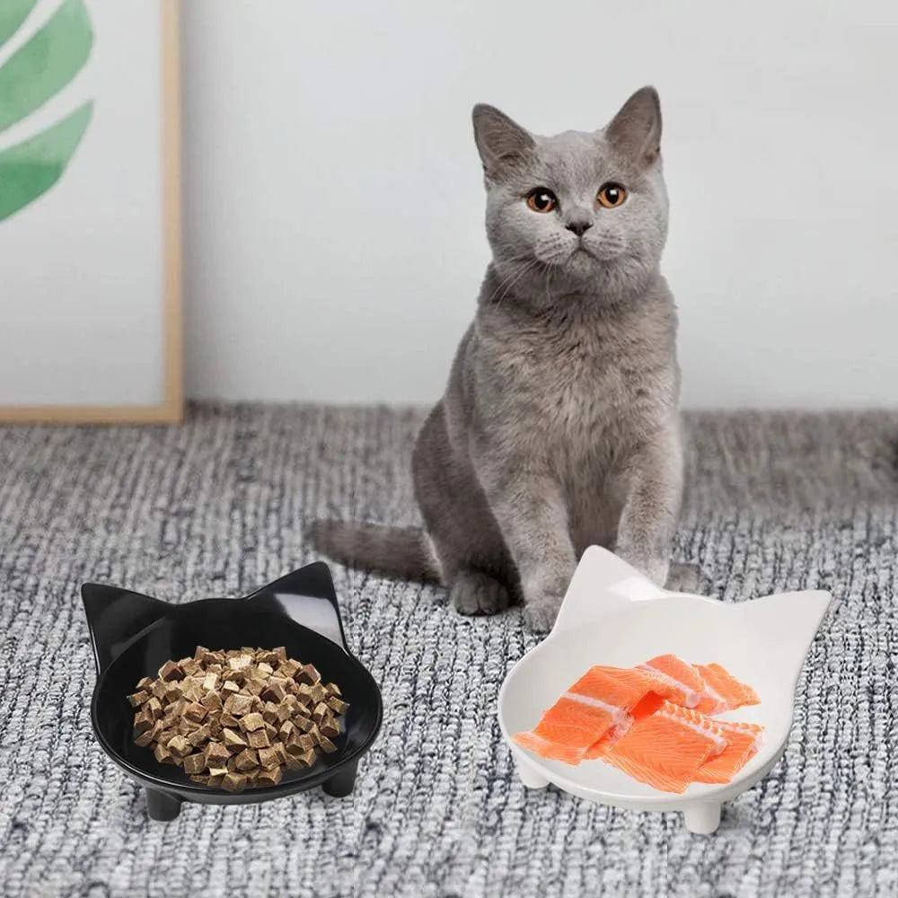 White and black shallow melamine pet bowls with non-slip rubber bases on a floor.