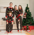 Matching red plaid Christmas pyjamas set for dad, mom, child, baby, and a dog laid out together