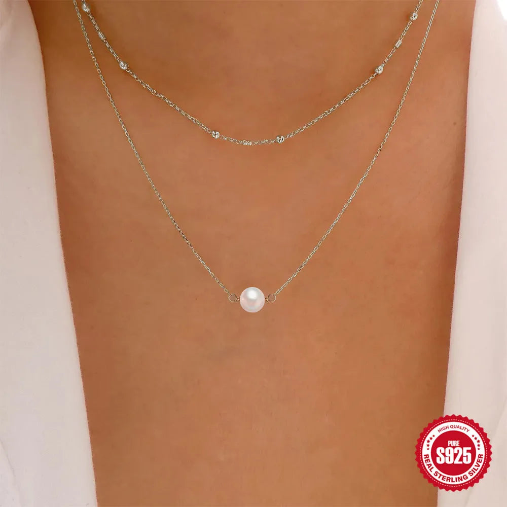 S925 sterling silver double layer necklace with twin pearls in gold or white gold finish featuring geometric pendant and ball bead chain.