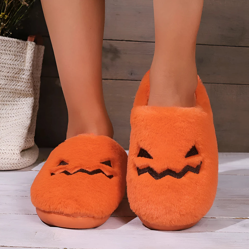 Orange Halloween pumpkin themed slippers with coral velvet upper and plush lining on a flat PVC sole.