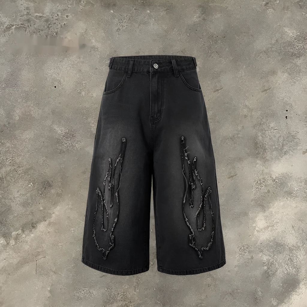 Men's black denim cropped shorts with red and yellow flame patch embroidery on the leg.