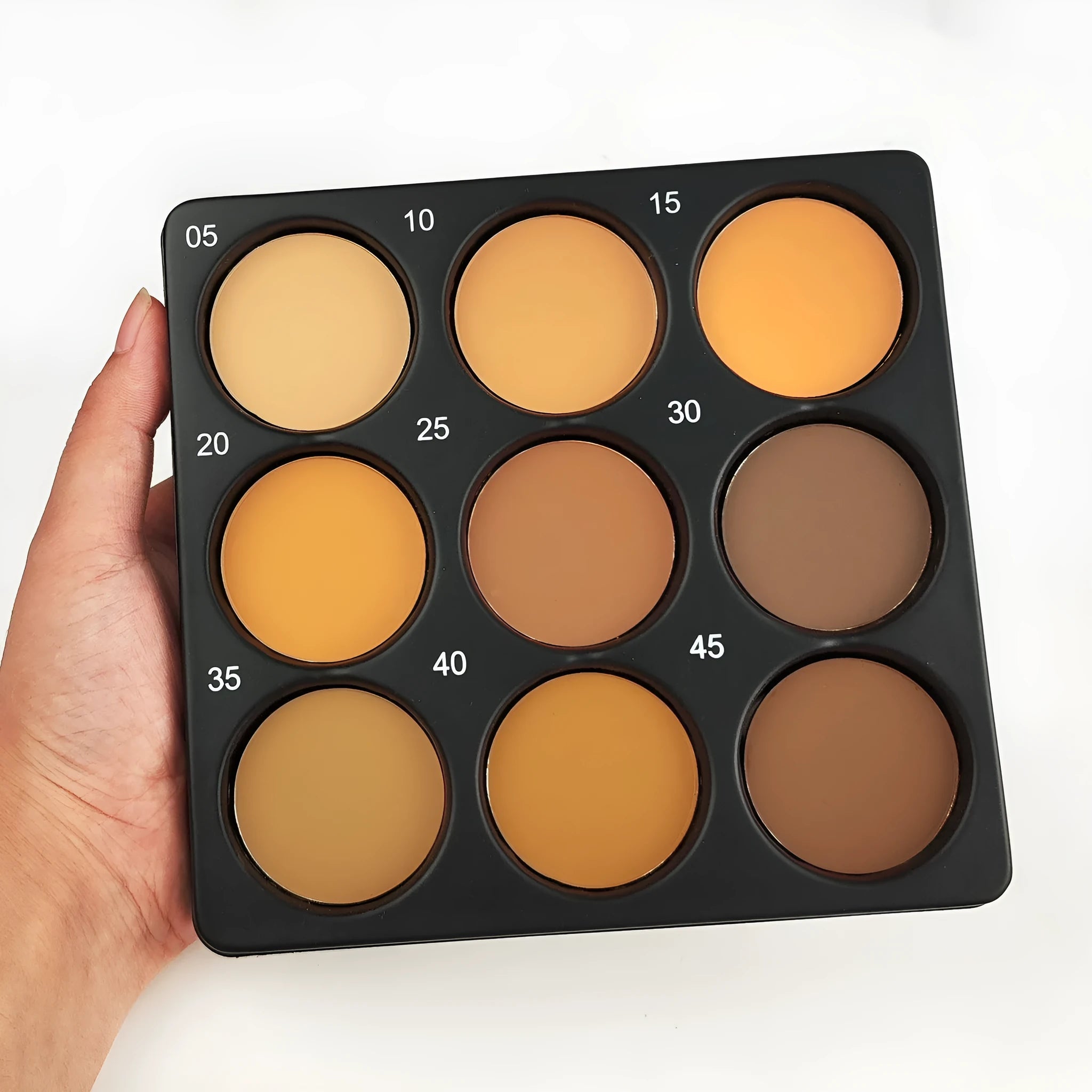 Open dark matte eyeshadow palette showing nine dark coloured pans with a repair disk.