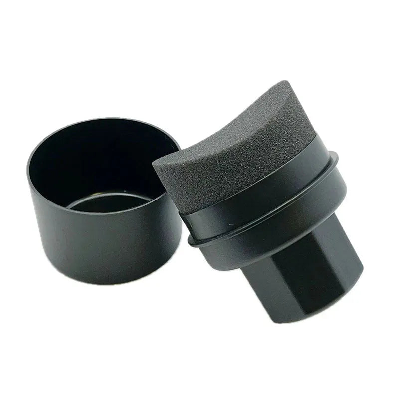Hand-held black and red car tyre polishing sponge brushes with lids on a garage workbench.