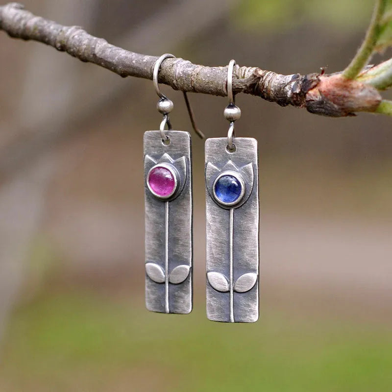 A pair of red sapphire earrings with an antique finish and geometric elliptical shape.