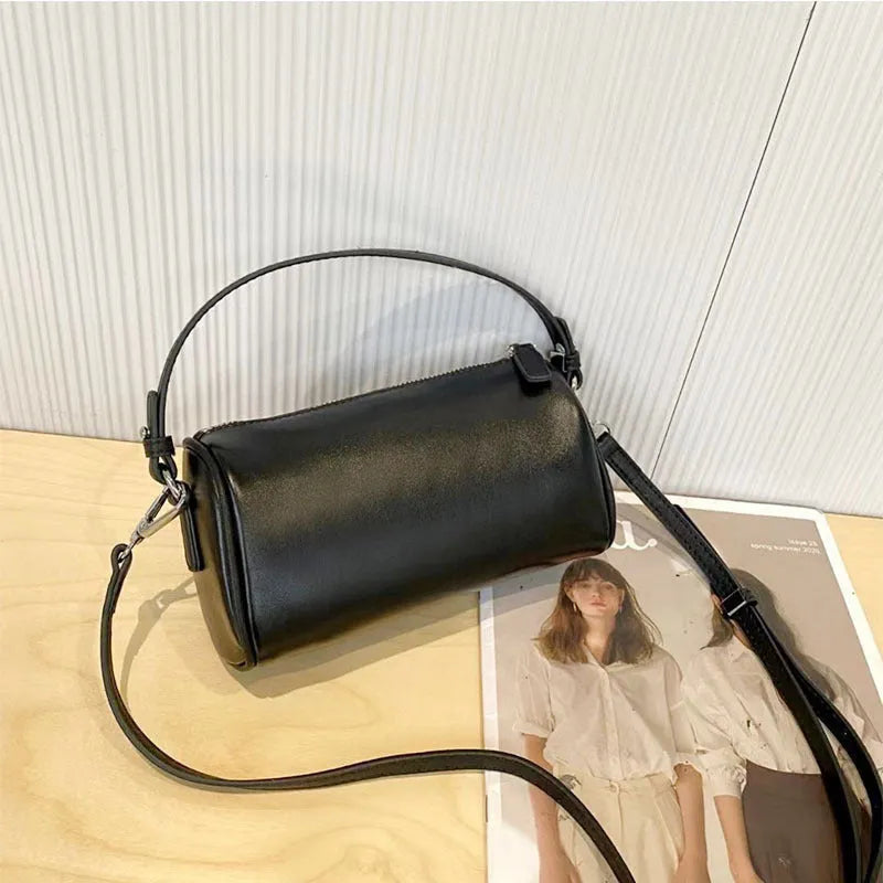 Vegetable-tanned leather crossbody phone bag with cylindrical shape and visible sewing thread detailing