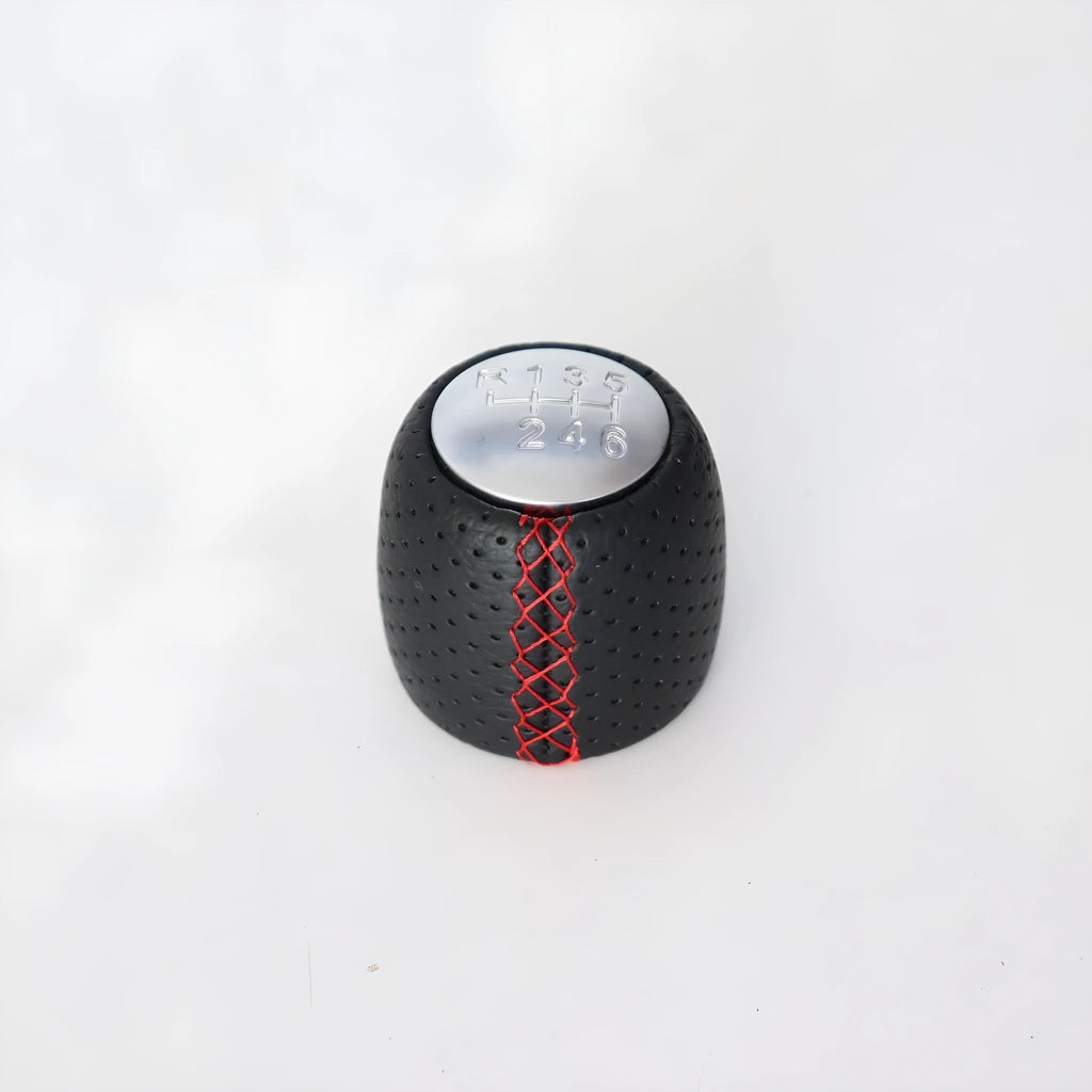 Sewn wrapped black perforated leather gear shift handball for Alpha vehicles on a silver cover.