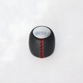 Sewn wrapped black perforated leather gear shift handball for Alpha vehicles on a silver cover.