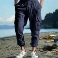 Man wearing loose, ankle-tied linen trousers in a solid colour with visible pockets.