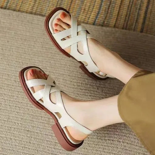 Women's black patent leather low heel sandals with square toe and cross ankle strap.