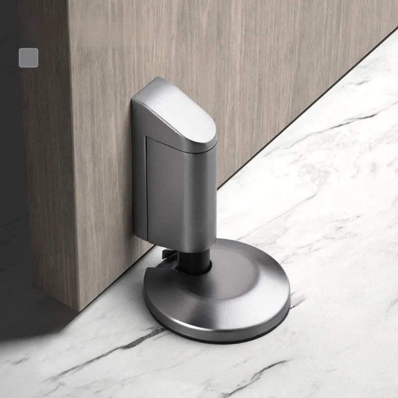 Modern zinc alloy invisible door stopper in brushed nickel finish on a wooden floor.