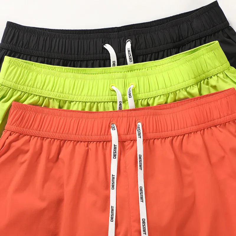 Men's loose orange beach shorts with elastic waistband on a sandy shore