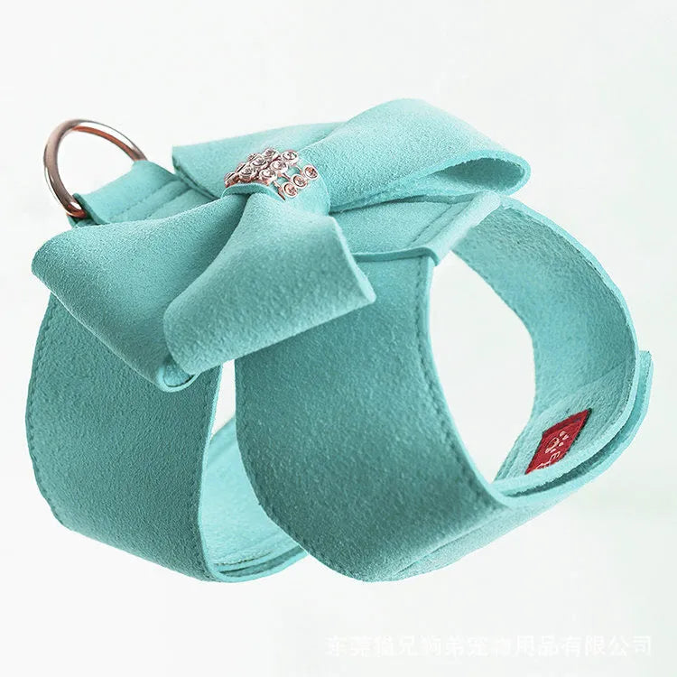 Puppy wearing a blue microfiber chest strap with a decorative bowknot, showing the adjustable lead attachment.