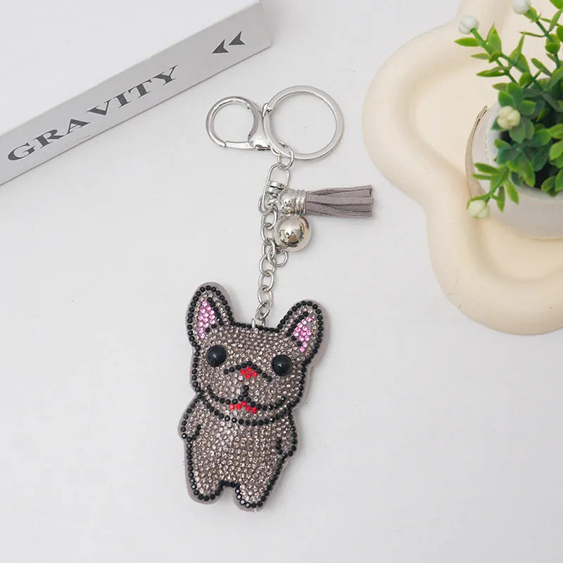 Close-up of a cartoon dog rhinestone keychain charm in alloy, showing sparkling details on a grey background.