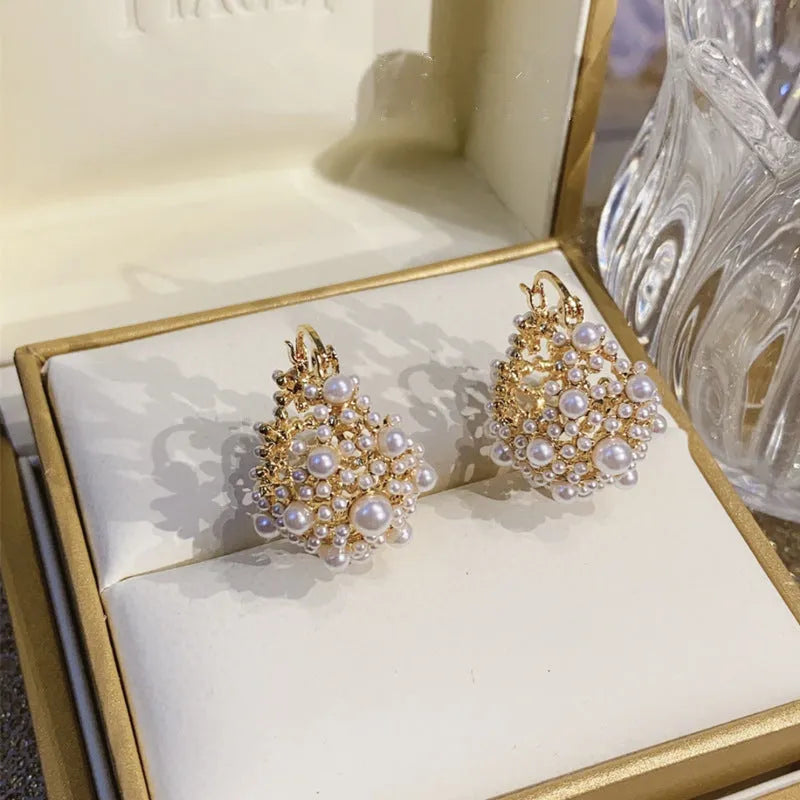 Gold-coloured copper flower basket earrings with rice-shaped bead decoration and pearl inlay detailing