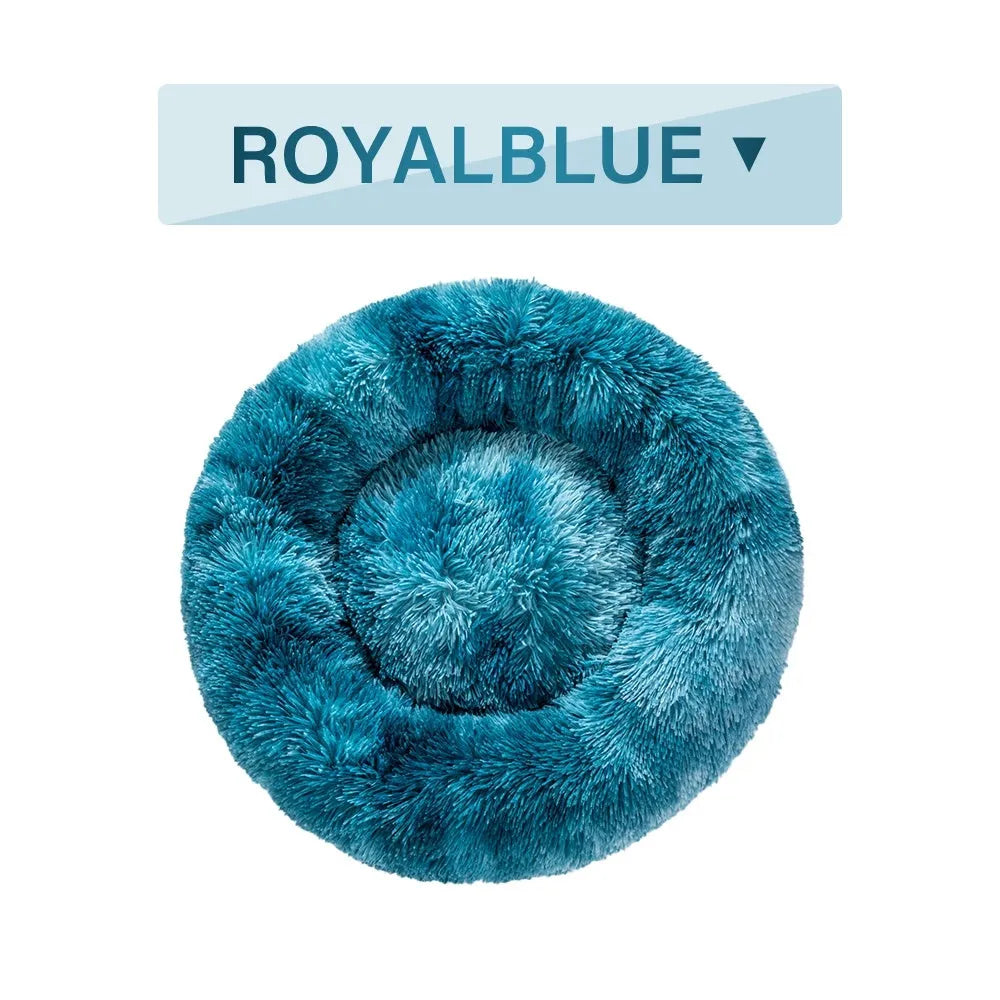 Fluffy donut-shaped dog bed in long plush material, shown in a light grey colour with a raised edge.