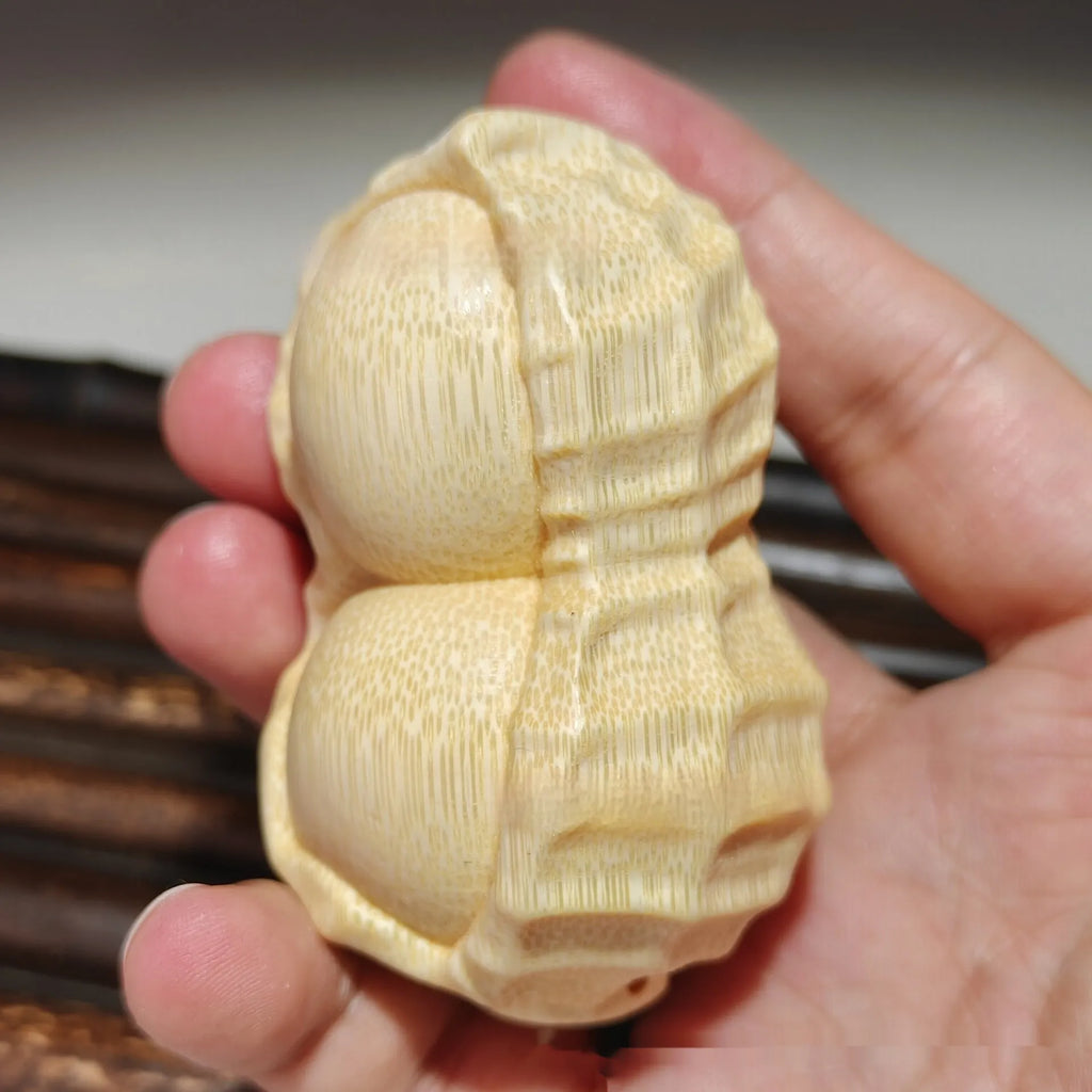 Solid natural bamboo hand-carved peanut ornament on a plain background.