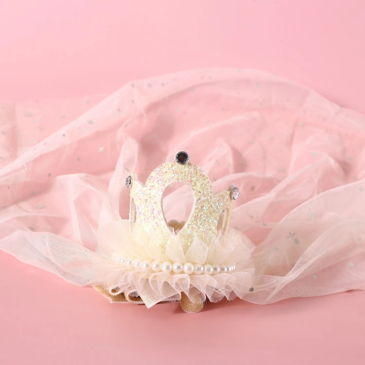 Pet cat wearing a princess crown headdress with a soft pink veil on a fabric headband.
