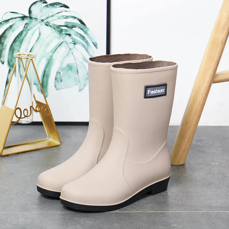 Women's mid-calf PVC rain boot in black on a wet surface.
