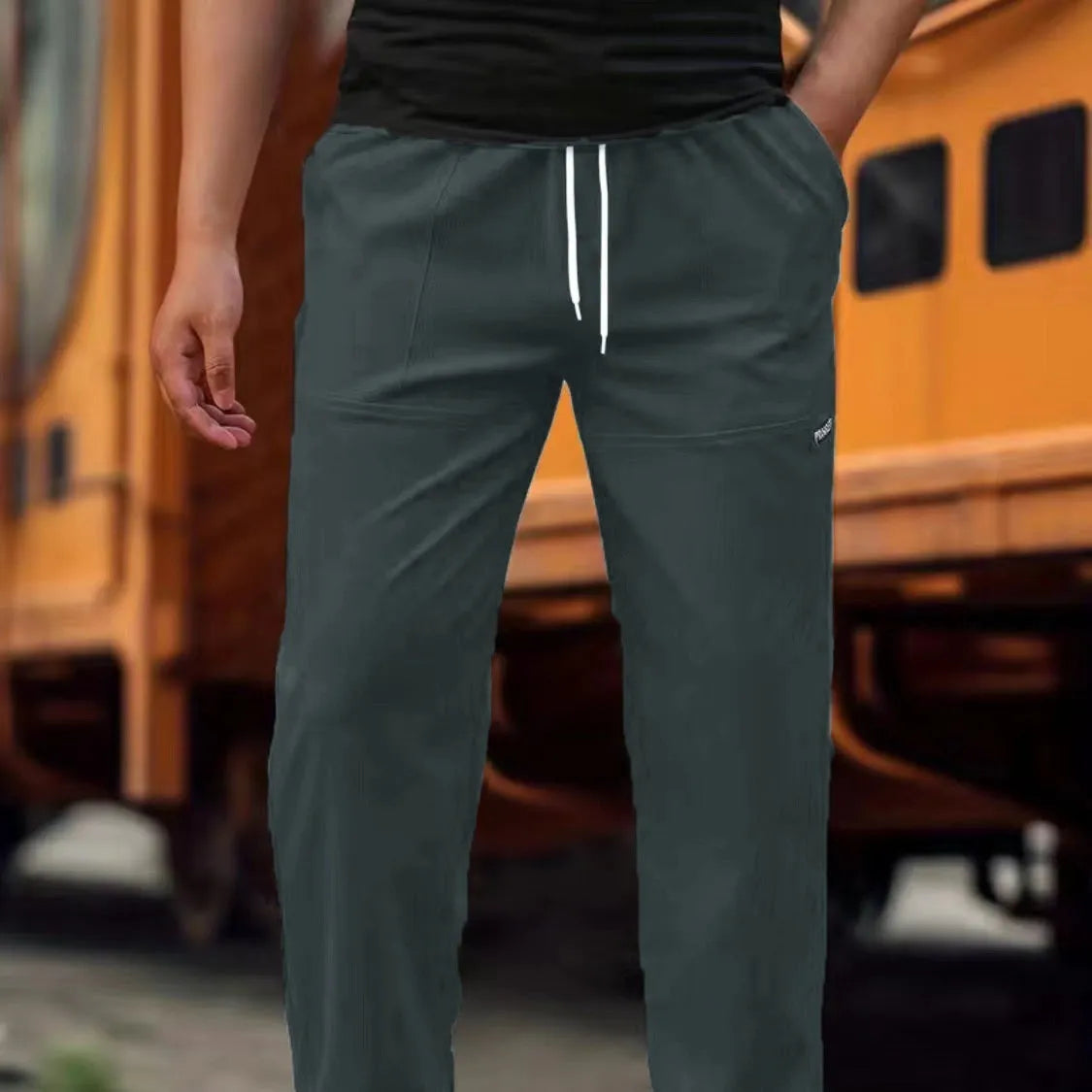 Men's polyester trousers in light grey, shown laid flat, suitable for spring and autumn wear.