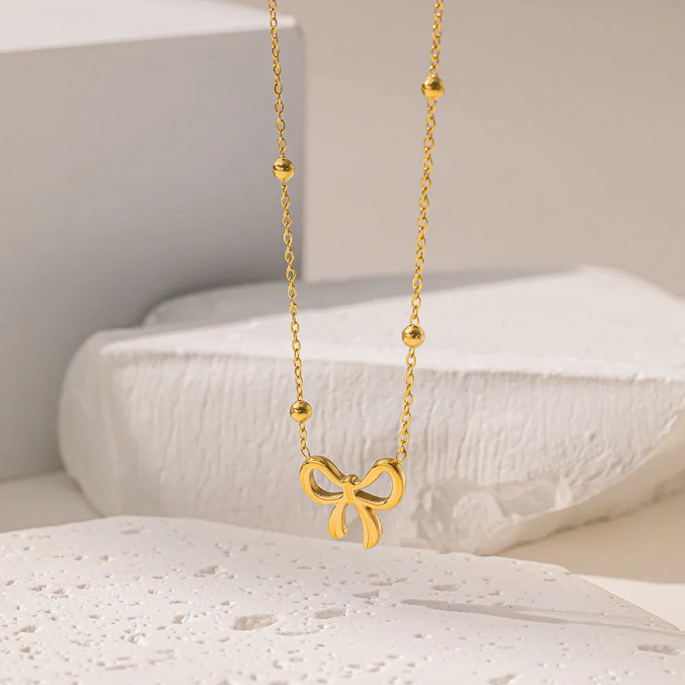 Gold electroplated titanium steel women's necklace with bow pendant and adjustable cross chain