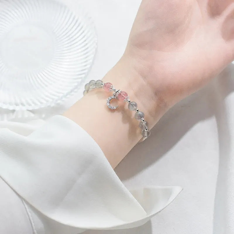 Simple handmade bracelet with round moonstone beads, a small crescent moon charm, and an adjustable metal clasp.