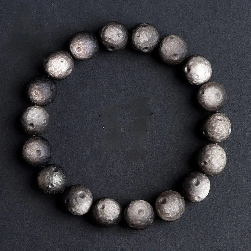 Natural obsidian crater ball bracelet with polished beads in silver or gold meteorite finish.