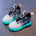 Blue children's roller skates with striped pattern and a rotating button fastener on a solid ground surface.