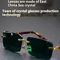 Dark green frameless crystal sunglasses shown with a glasses case and lens cloth.