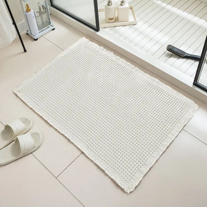 Square checkered-pattern non-slip bathroom carpet in a neutral colour on tiled floor.