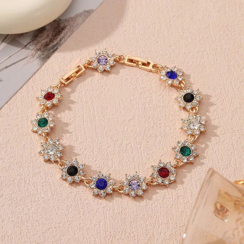 A gold or silver electroplated zinc alloy flower bracelet with coloured gems.
